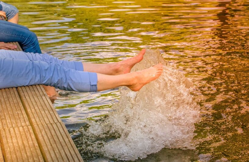 Glückliche Menschen planschen mit ihren Füßen einem sauberen Schwimmteich Naturpool, Schwimmteichreinigung, Reinigung Naturpool, Teichreinigung24, Teichpflege Berlin Brandenburg