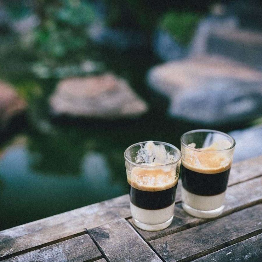 Zwei Gläser Kaffee am Teichrand mit Natur im Hintergrund