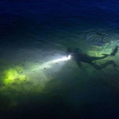 Taucher mit Unterwasserlampe in einem nächtlichen See